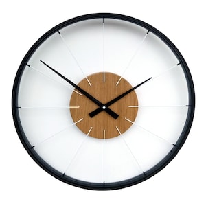 Pode incluir: Um relógio preto e branco com um centro de madeira. O relógio tem um design circular com raios brancos que irradiam do centro.