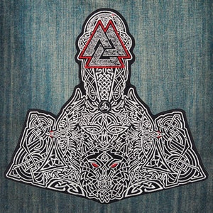 Op de afbeelding: Een zwart-wit geborduurde patch met een gedetailleerd Vikingontwerp. De patch bevat een rood en wit driehoekig symbool, ingewikkeld knoopwerk en een wolfskop met rode ogen. Op een blauwe denim achtergrond.