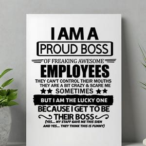 Könnte beinhalten: Ein weißes rechteckiges Schild mit schwarzem Text. Es lautet: "I AM A PROUD BOSS of freaking awesome employees." Der Text setzt sich mit einem Humor über Angestellte und den Chef fort. Das Schild wird an einer weißen Wand angezeigt.