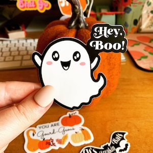 May include: A white ghost sticker with a cute cartoon face and the text "Hey Boo!" on a pumpkin.