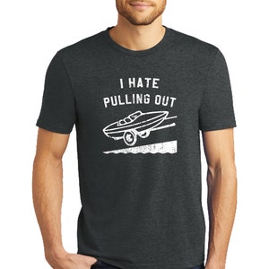 May include: A dark heather grey t-shirt with a white distressed graphic of a boat being pulled out of the water. The text "I hate pulling out" is above the graphic.
