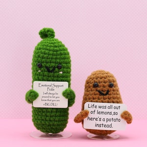 May include: A green crocheted pickle holding a sign that says "Emotional Support Pickle I will always be around to let you know that you are a BIG DILL" and a brown crocheted potato holding a sign that says "Life was all out of lemons, so here's a potato instead."
