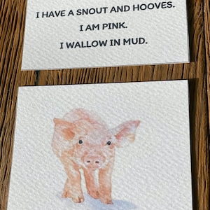 May include: A watercolor illustration of a pink piglet with a snout and hooves. The piglet is standing on a white background. The text "I have a snout and hooves. I am pink. I wallow in mud." is written above the piglet.