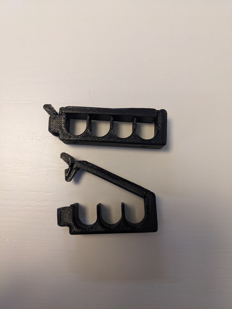 May include: Two black plastic cable organizers with multiple slots for holding cables. The organizers are designed to be mounted on a wall or surface.