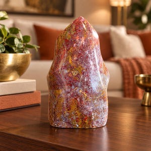 May include: A polished, flame-shaped stone sculpture featuring a vibrant mix of deep red, golden yellow, and translucent white mineral inclusions. The surface is smooth and glossy, displaying intricate, swirling patterns of color throughout.