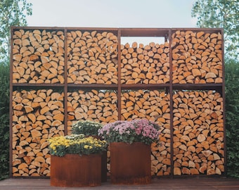 Può includere: Un muro rustico in legno fatto di tronchi impilati, con tre vasi di metallo arrugginito che contengono fiori colorati. I vasi sono posizionati davanti al muro, creando una scena decorativa e naturale.