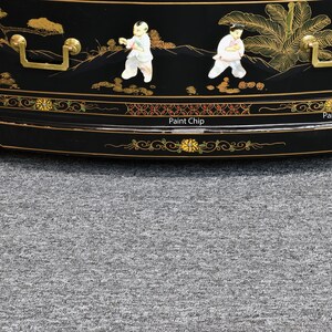Pode incluir: Um arm&aacute;rio de madeira lacado de preto com detalhes dourados e pintados &agrave; m&atilde;o. O arm&aacute;rio apresenta uma frente curva e tr&ecirc;s gavetas com puxadores dourados. O arm&aacute;rio &eacute; decorado com um desenho floral e figuras em estilo chin&ecirc;s tradicional.