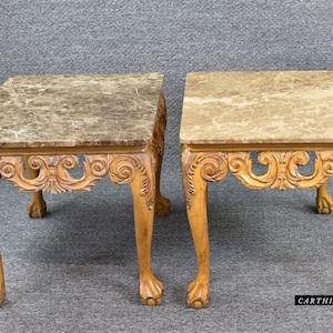 May include: A pair of ornate wooden end tables with marble tops. The tables have carved details and claw feet.