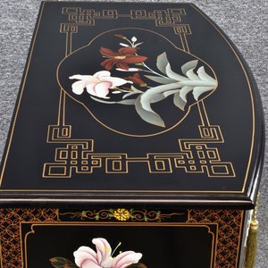 Pode incluir: Arm&aacute;rio lacado de preto com detalhes dourados e desenhos florais. O arm&aacute;rio apresenta uma parte superior curva e detalhes intrincados.