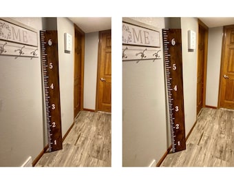May include: A wooden growth chart with white numbers from 1 to 6. The chart is mounted on a wall in a hallway with a wooden floor. The chart is next to a white sign with the word "HOME" on it.