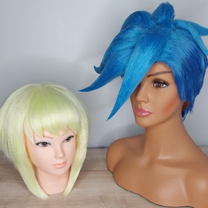 Può includere: Due teste di manichino con parrucche. Una parrucca è di un blu brillante e acconciata in uno stile appuntito e asimmetrico. L'altra parrucca è di un giallo pallido e acconciata in un bob corto e dritto.