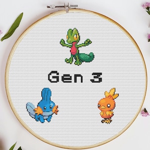 Pode incluir: Um aro de bordado branco com um desenho de ponto cruz que apresenta três personagens Pokémon da terceira geração: Treecko, Mudkip e Torchic. O texto "Gen 3" está bordado em preto abaixo dos personagens.