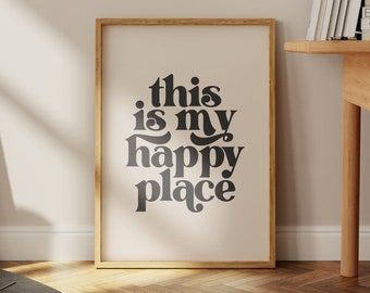 May include: A framed print with the text "this is my happy place" in a retro font style. The print is on a cream background with a black frame.