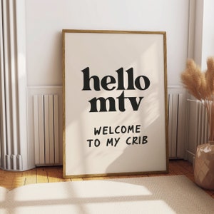Peut inclure: Une impression encadrée avec le texte "hello mtv welcome to my crib" en lettres noires sur un fond crème.