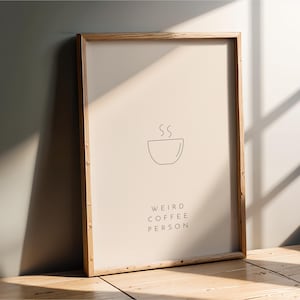 May include: A framed print with a minimalist line drawing of a steaming cup of coffee and the text "Weird Coffee Person".
