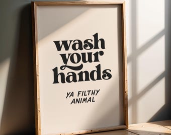 May include: A framed print with the text "Wash your hands Ya Filthy Animal" in black lettering on a beige background.