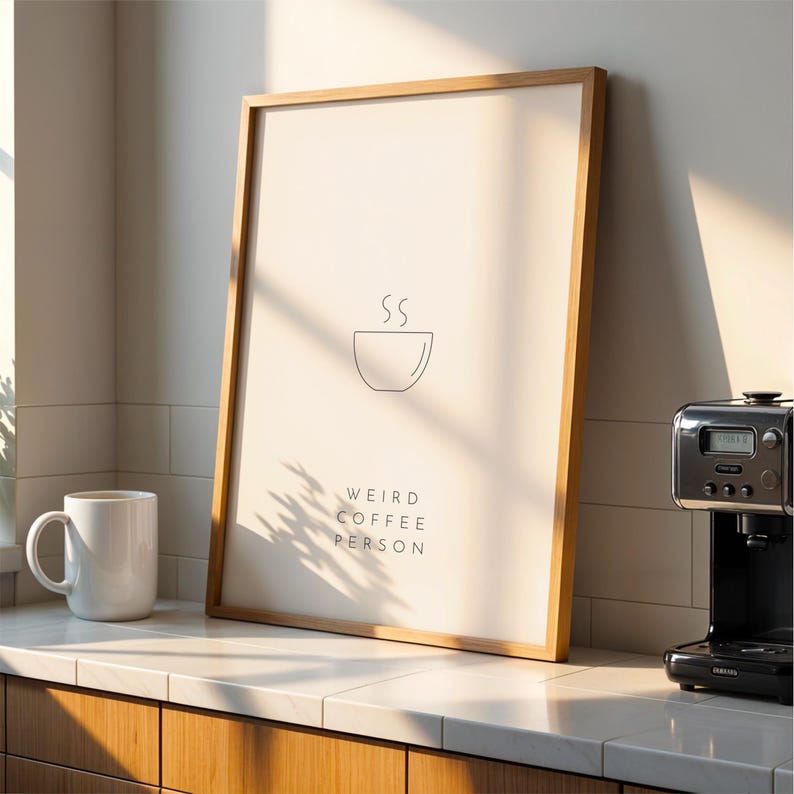 May include: A framed print featuring a minimalist design of a coffee cup with steam rising from it. The text "Weird Coffee Person" is below the image.
