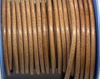 May include: A spool of brown leather cord. The cord is wound tightly around the spool and is ready to be used for crafting projects.