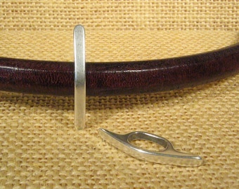 May include: Two silver metal belt buckle keepers. One is a straight piece and the other is a curved piece with a hole in the center.