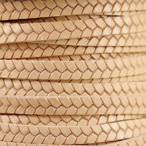 May include: Close-up of a beige leather cord with a braided pattern. The cord is woven in a diamond pattern.