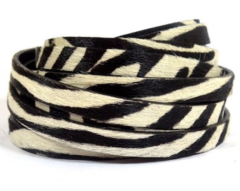 May include: Black and white zebra print leather cord, rolled up and ready to be used for crafting projects.