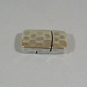 May include: Silver-toned metal clasp with a hammered texture. The clasp is designed to be used for necklaces or bracelets.