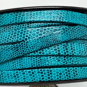 以下が含まれることがあります： テクスチャ加工が施された蛇のような模様のターコイズブルーの革紐。紐は巻かれており、幅は約1.2cmです。