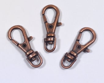 May include: Three antique copper-colored metal swivel clasps or hooks. These are great for attaching to keychains, bags, or other items.