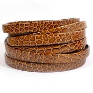 May include: A close-up of a stack of brown leather cord with a crocodile embossed pattern.