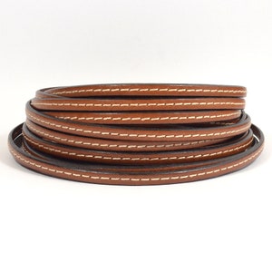 May include: A roll of brown leather cord with white stitching. The cord is approximately 5mm wide.