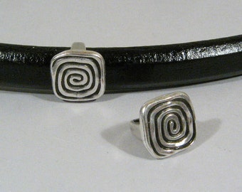 May include: Two silver-toned metal rings with a spiral design. The rings are square shaped and have a raised spiral pattern.