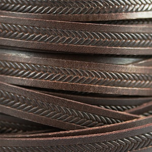 May include: Close-up of brown leather cord with a braided design. The cord is rolled up and the braided design is visible on the surface.
