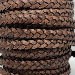 Peut inclure: Gros plan d'une bobine de cordon en cuir tressé de couleur marron foncé. Le cordon est finement tissé, révélant une surface texturée. Ce cordon en cuir est adapté à la création de bijoux, à l'artisanat et à d'autres projets créatifs.