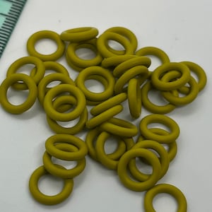 May include: A pile of 20 small, olive green rubber o-rings.