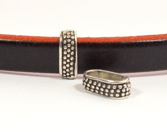 May include: Two silver metal end caps for leather straps. The end caps have a textured design with small dots.