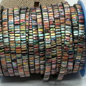 May include: A roll of iridescent leather cord with a multi-colored, striped pattern. The cord is wound around a spool.