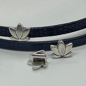 May include: Three silver-toned lotus flower charms for a leather bracelet. The charms are detailed and have a slightly textured finish.