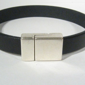 May include: A black leather bracelet with a silver magnetic clasp.