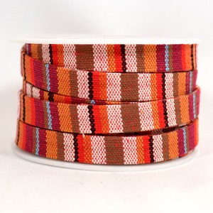 May include: A spool of orange, brown, and white striped fabric trim. The trim is woven with a variety of colors and patterns.
