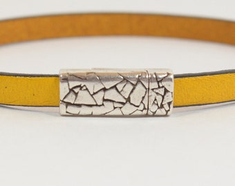 May include: A yellow leather bracelet with a silver magnetic clasp. The clasp has a textured, cracked design.