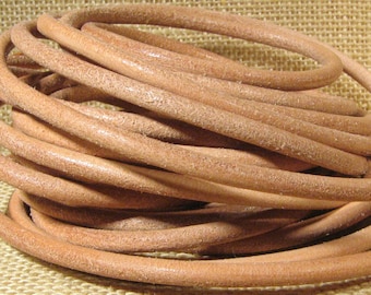 May include: A close-up of a coil of light brown leather cord. The cord is smooth and supple, and it is perfect for crafting jewelry, belts, or other leather goods.