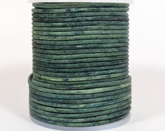 May include: A spool of dark green leather cord. The cord is wound tightly around a white plastic spool.