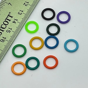 May include: Assortment of ten colorful plastic rings, including green, orange, yellow, blue, purple, and black. The rings are arranged on a white surface.