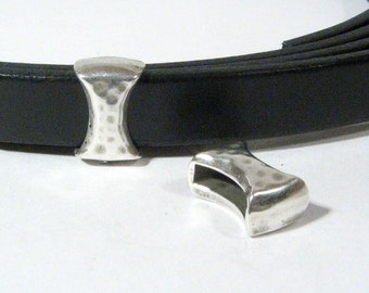 May include: Two silver metal belt end caps with a hammered texture. The caps are designed to be used with a leather strap.