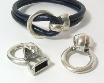May include: A set of silver-toned metal clasps for leather bracelets. The set includes a clasp with a ring, a clasp with a loop, and a clasp with a knot design. The clasps are designed to be used with leather bracelets.