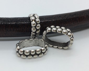 May include: Three silver metal bead spacers for leather bracelets. The spacers are round and have a smooth, shiny finish.