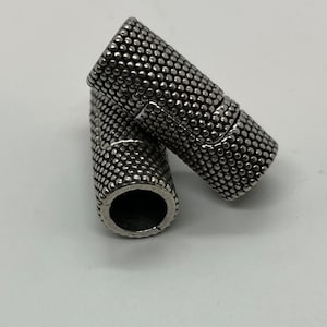 May include: Two silver metal cord end caps with a textured surface.