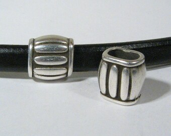 May include: Two silver metal beads with a ridged design. The beads are on a black leather strap.