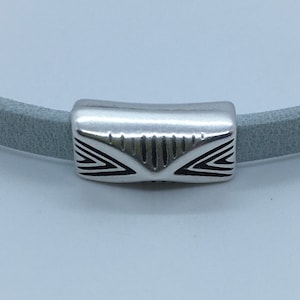 Op de afbeelding: Zilveren metalen kraal met een geometrisch ontwerp, geschikt voor gebruik bij het maken van sieraden.