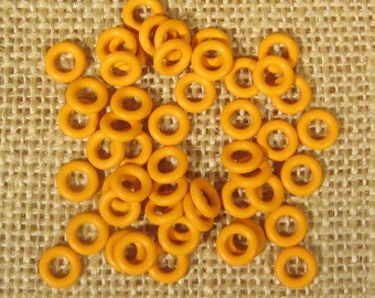 May include: A large group of orange rubber O-rings, scattered on a brown burlap surface.